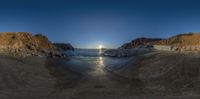 a fish eye image of a beach during sunset with two boats in the ocean and the cliffs in the background