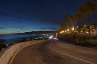 the coast with waves is at the right of this photo, a person riding his motorcycle on the street