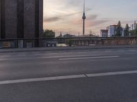 a bike sits on the road near a bridge and buildings in a city at sunset