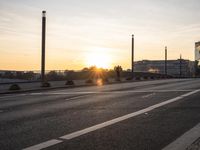 sunset over an empty highway with vehicles waiting at an intersection on either side of it