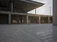 a small fire hydrant on the ground by a building with benches and steps at sunset