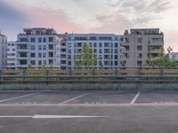 the parking lot in front of the apartment blocks at sunset with no one walking on it