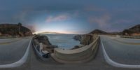 a panoramic image of the ocean at sunset on a bridge overlooking the ocean