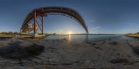 there is a 360 - angle view of the bridge from below the water line at sunset