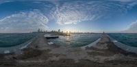 the sun is setting over the city and ocean waters as seen in this fish eye photograph