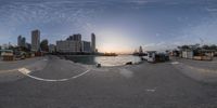 360 - view camera on the beach looking at a city skyline during sunset with a skateboarder