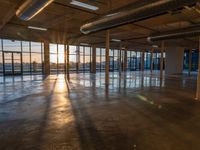 the sun setting in the building is seen through the windows and floor glass doors of the room