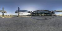 a wide angle view of the sun in front of a train station building while it's going down