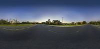 a wide angle photograph shows a road in the sunset with a city in the distance