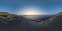 the camera is taking a picture of a curve at sunset with a view of the ocean