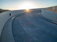 the sun is setting over a curved walkway in the desert style of town parkland