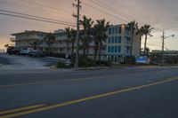 a street sign in front of a white building on a beach side town square at sunset