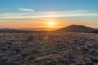 the sun shines brightly in the desert at sunset with a large field of dry grass