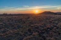 the sun shines brightly in the desert at sunset with a large field of dry grass