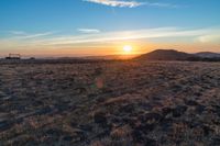 the sun shines brightly in the desert at sunset with a large field of dry grass