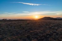 the sun shines brightly in the desert at sunset with a large field of dry grass
