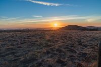 the sun shines brightly in the desert at sunset with a large field of dry grass