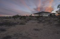 a sunset is seen in the desert setting of a home in southern california, where many people are out in the country