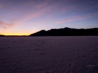 the view of the desert from an open beach at sunset time, with footprints in the sand