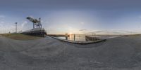 a 360 view of the sunset on a small dock near a body of water with water and power lines behind