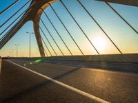 a car driving across a large bridge in the sun setting over the road and the sky