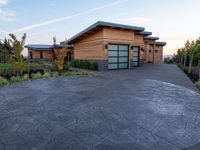 the front driveway has cement and pavers in it at sunset, showing a stone driveway