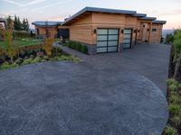 the front driveway has cement and pavers in it at sunset, showing a stone driveway