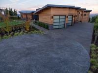 the front driveway has cement and pavers in it at sunset, showing a stone driveway