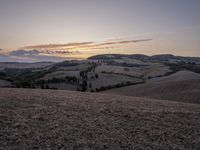 an empty field with a castle in the background at sunset in italy by steve berkell