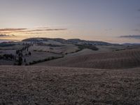 an empty field with a castle in the background at sunset in italy by steve berkell