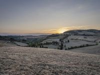 an empty field with a castle in the background at sunset in italy by steve berkell