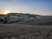 an empty field with a castle in the background at sunset in italy by steve berkell