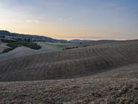 an empty field with a castle in the background at sunset in italy by steve berkell