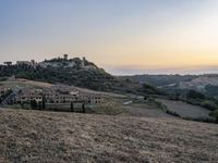 an empty field with a castle in the background at sunset in italy by steve berkell