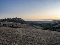 an empty field with a castle in the background at sunset in italy by steve berkell