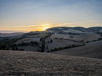 an empty field with a castle in the background at sunset in italy by steve berkell