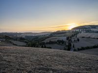 an empty field with a castle in the background at sunset in italy by steve berkell