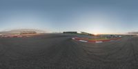 this is the sun setting in an empty track in a race field, as viewed through the lens