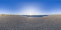 this is a panorama of a beach and ocean with sun setting in the background as seen on the 360 - vr camera