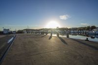 a boat dock with the sun setting on the horizon next to boats docked in the marina