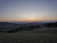 the sun is setting behind the hills in the country side of italy for people to admire