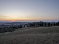 the sun is setting behind the hills in the country side of italy for people to admire