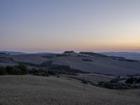 the sun is setting behind the hills in the country side of italy for people to admire