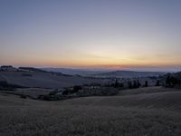 the sun is setting behind the hills in the country side of italy for people to admire