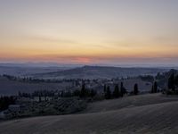 the sun is setting behind the hills in the country side of italy for people to admire