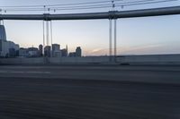 a long bridge with buildings in the background at sunset / taken from an suv on highway