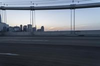 a long bridge with buildings in the background at sunset / taken from an suv on highway