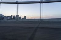 a long bridge with buildings in the background at sunset / taken from an suv on highway