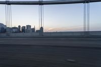 a long bridge with buildings in the background at sunset / taken from an suv on highway