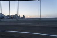 a long bridge with buildings in the background at sunset / taken from an suv on highway